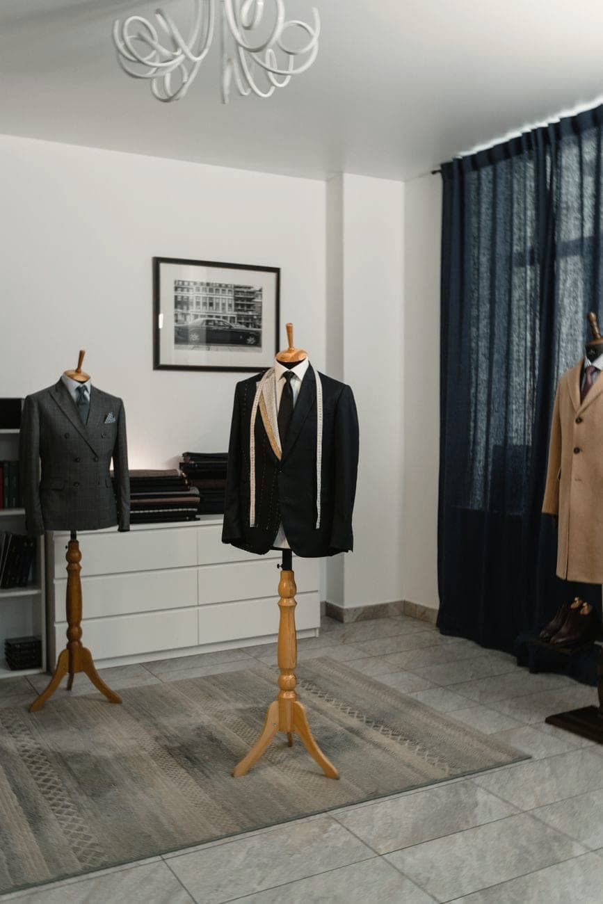 Maatkostuums op paspoppen in een kleermakersatelier