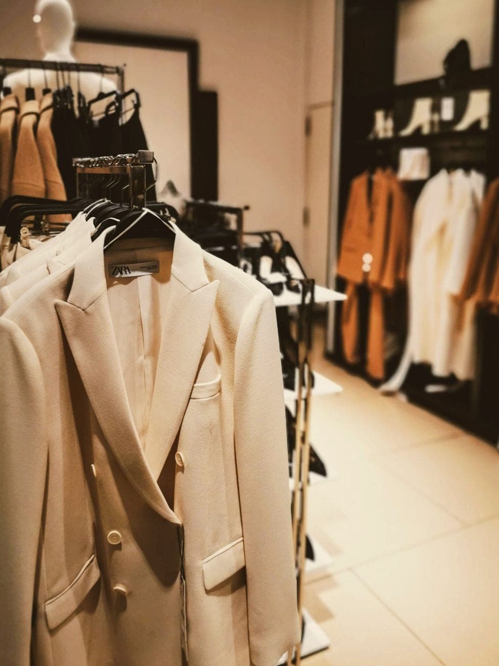 Beige blazers en jassen aan een rek in een modewinkel