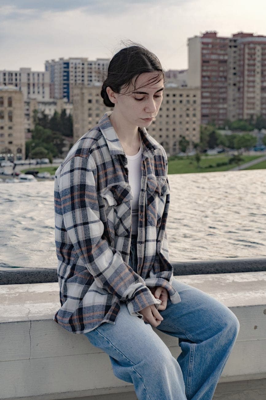 Jongere in een geruit flanellen hemd en een wijde jeans aan het water