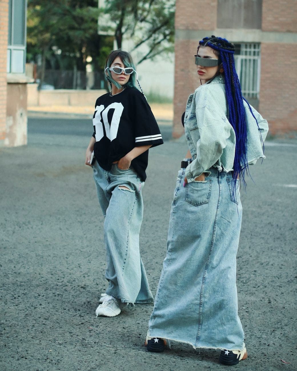 Twee vrouwen in lange jeansrokken, een oversized shirt en een jeansjasje op straat