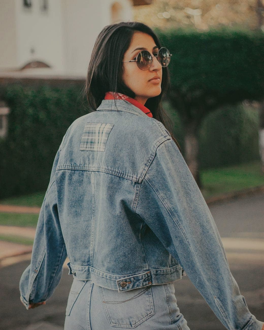 Vrouw in een oversized lichtblauw jeansjasje met zonnebril