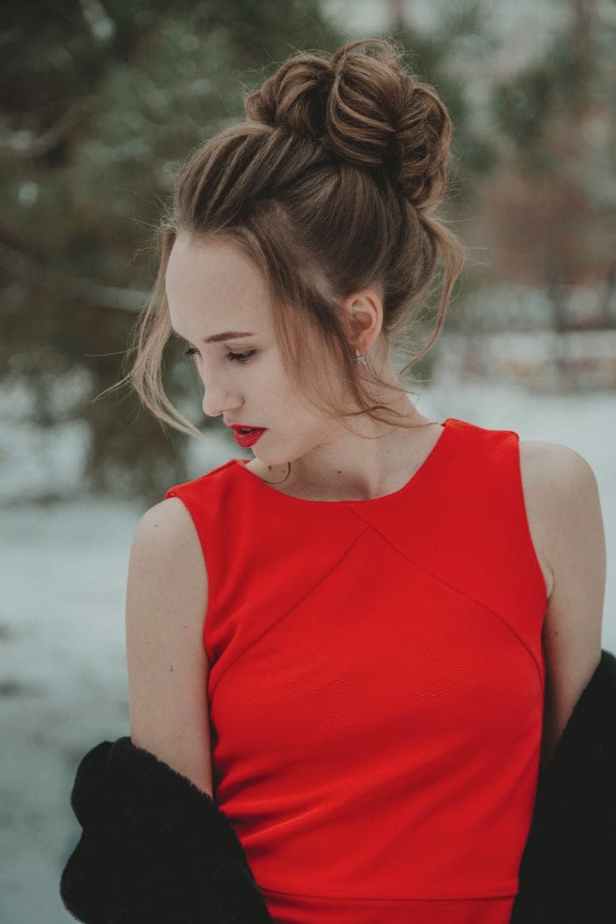 Vrouw in een rood mouwloos kleed met een zwarte jas over de schouders in de winter
