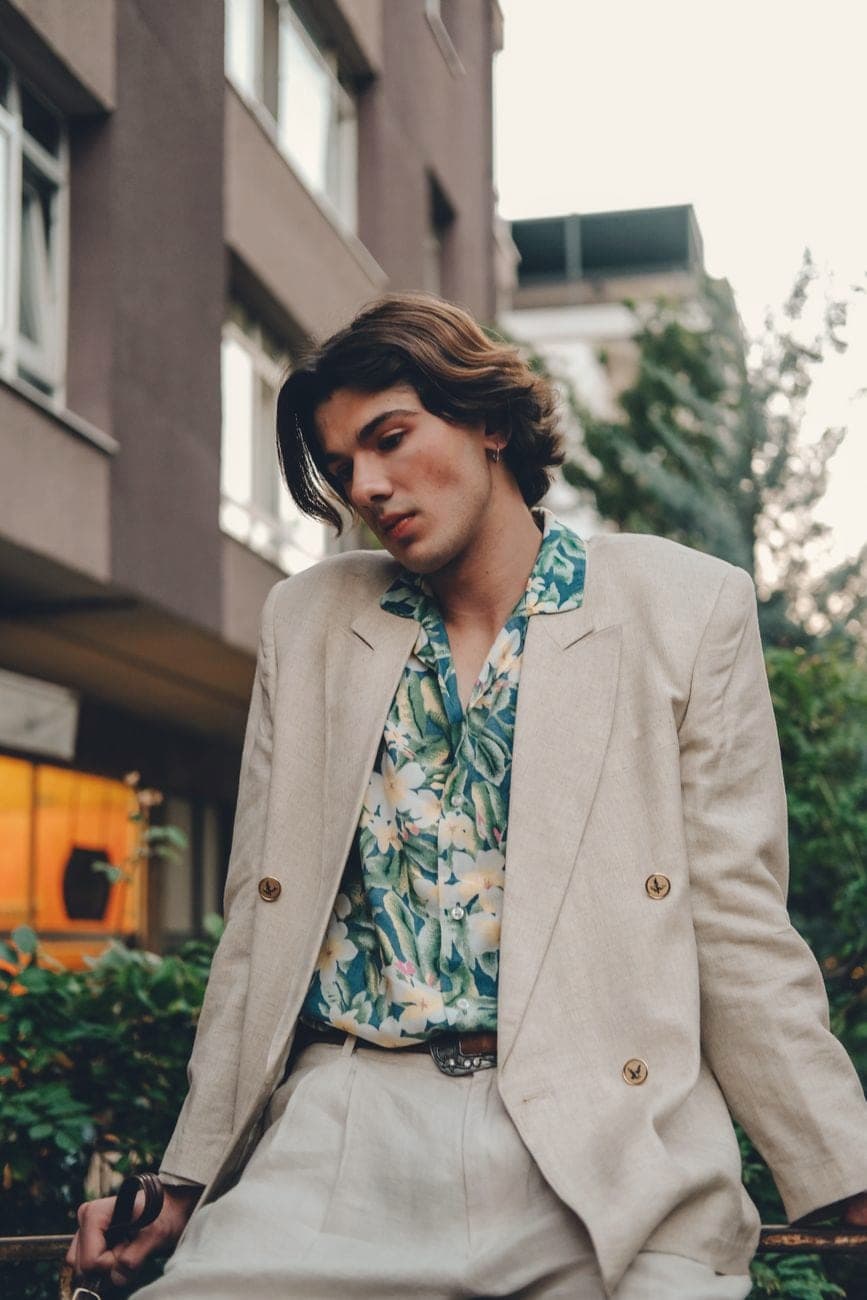 Man in een beige linnen kostuum met een hemd met bladerprint