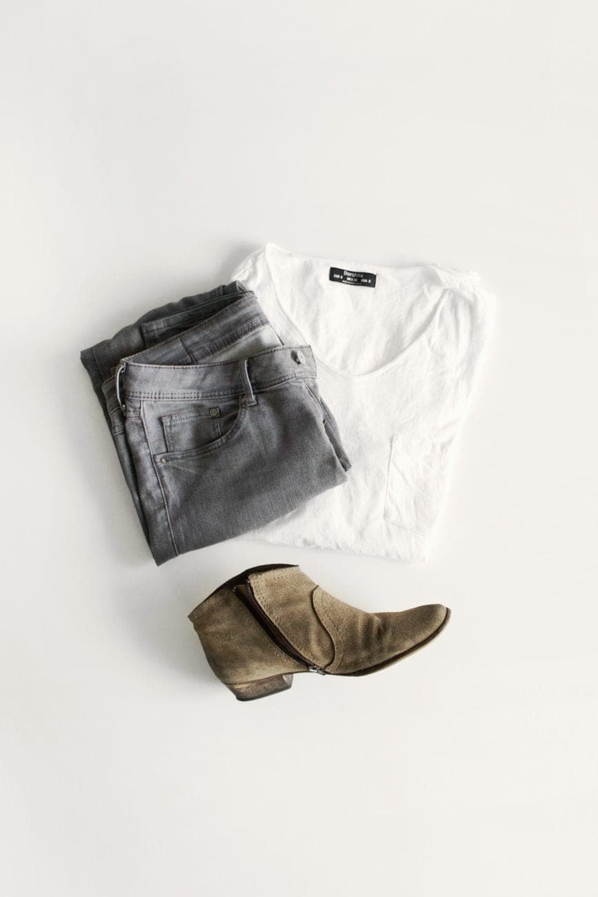 Opgevouwen kleding en accessoires in neutrale tinten op een tafel